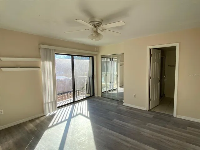 a view of a hallway with wooden floor and a ceiling fan