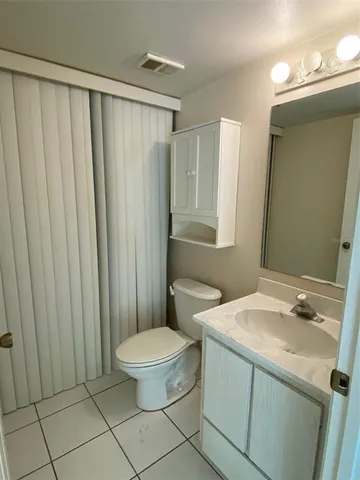 a bathroom with a sink a toilet a mirror and shower curtain