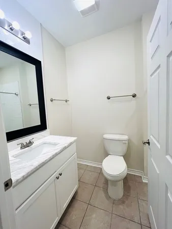 a bathroom with a granite countertop sink toilet and mirror