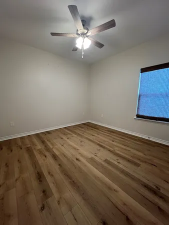 an empty room with wooden floor and fan