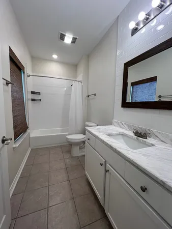 a bathroom with a granite countertop sink mirror vanity and toilet