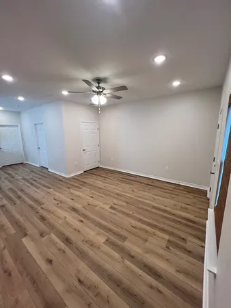 a view of an empty room with wooden floor and chandelier