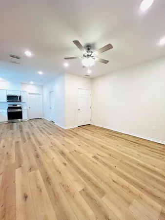 a view of empty room with wooden floor and ceiling fan
