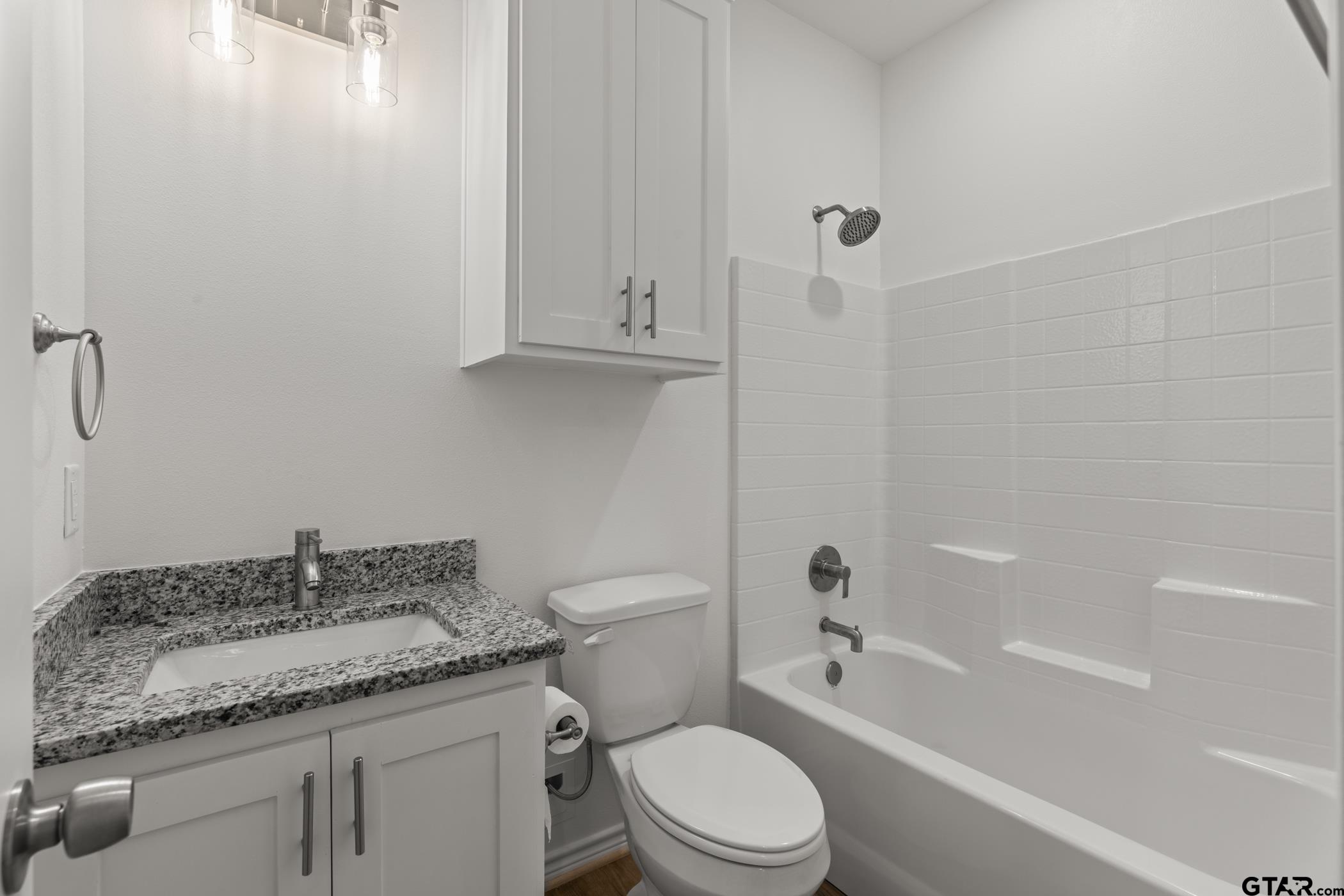 712 West 3rd Tyler, TX 75701 - Photo 23 of 28 a bathroom with a granite countertop toilet a sink and a bathtub