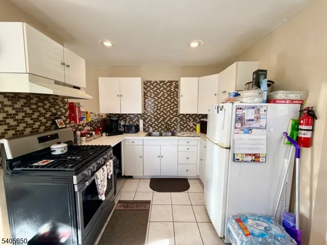 a kitchen with stainless steel appliances a stove and white cabinets