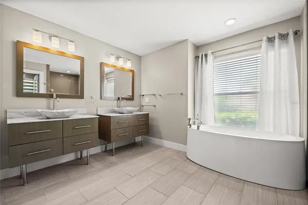 a bathroom with a double vanity sink mirror and bathtub