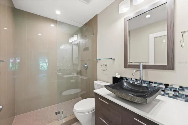 a bathroom with a granite countertop sink a toilet a mirror and shower