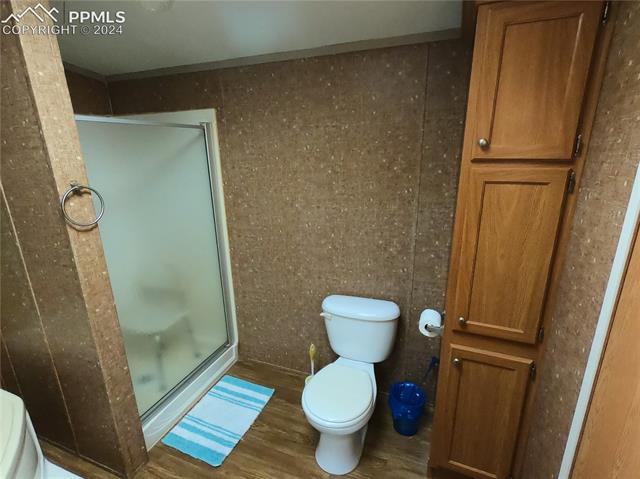 609 3rd Avenue Romeo, CO 81148 - Photo 9 of 16 Bathroom featuring toilet, hardwood / wood-style floors, and a shower with shower door