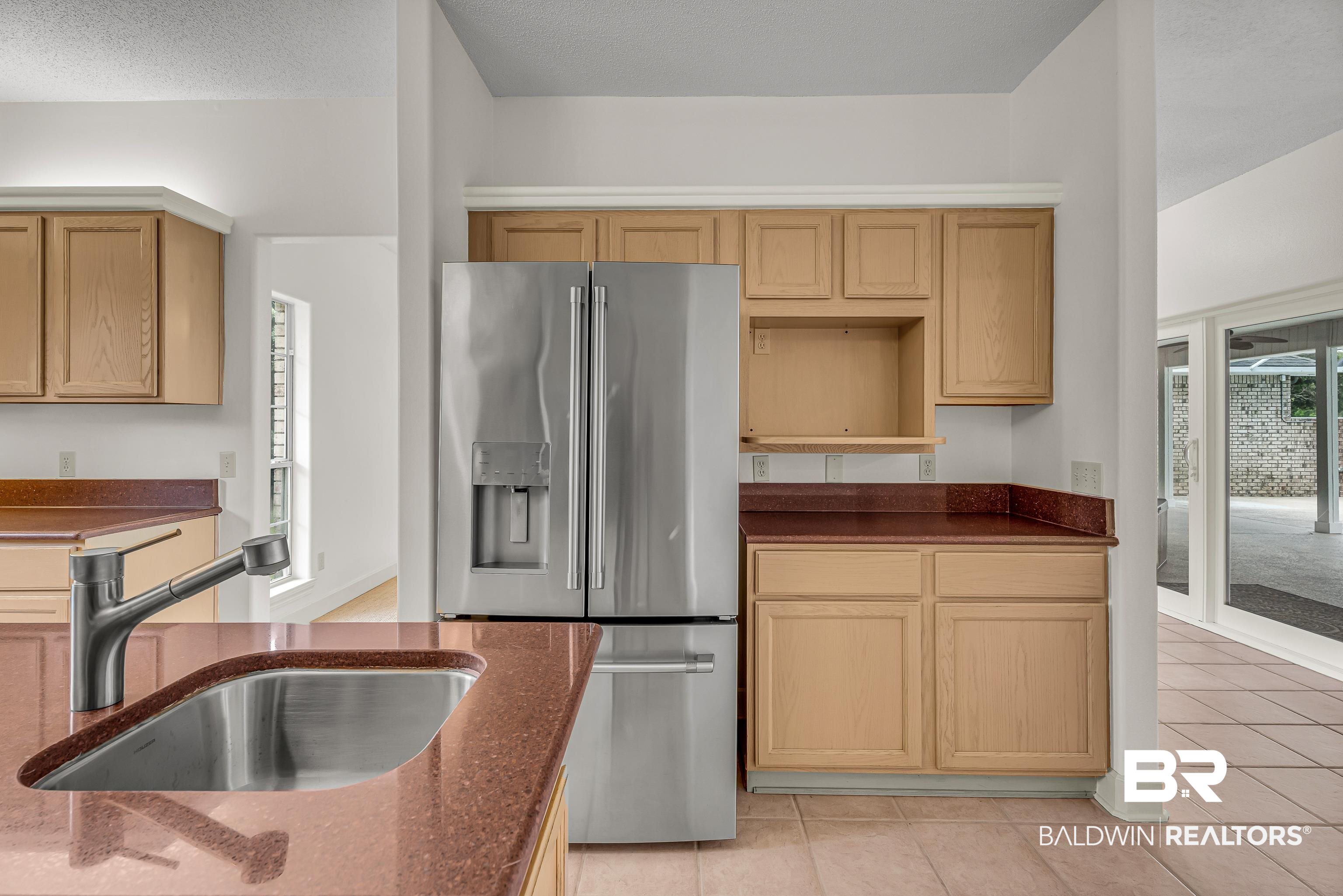 9530 Pilgrim Drive Elberta, AL 36530 - Photo 17 of 61 Kitchen featuring dark stone counters, light tile patterned floors, a sink, and stainless steel fridge with ice dispenser