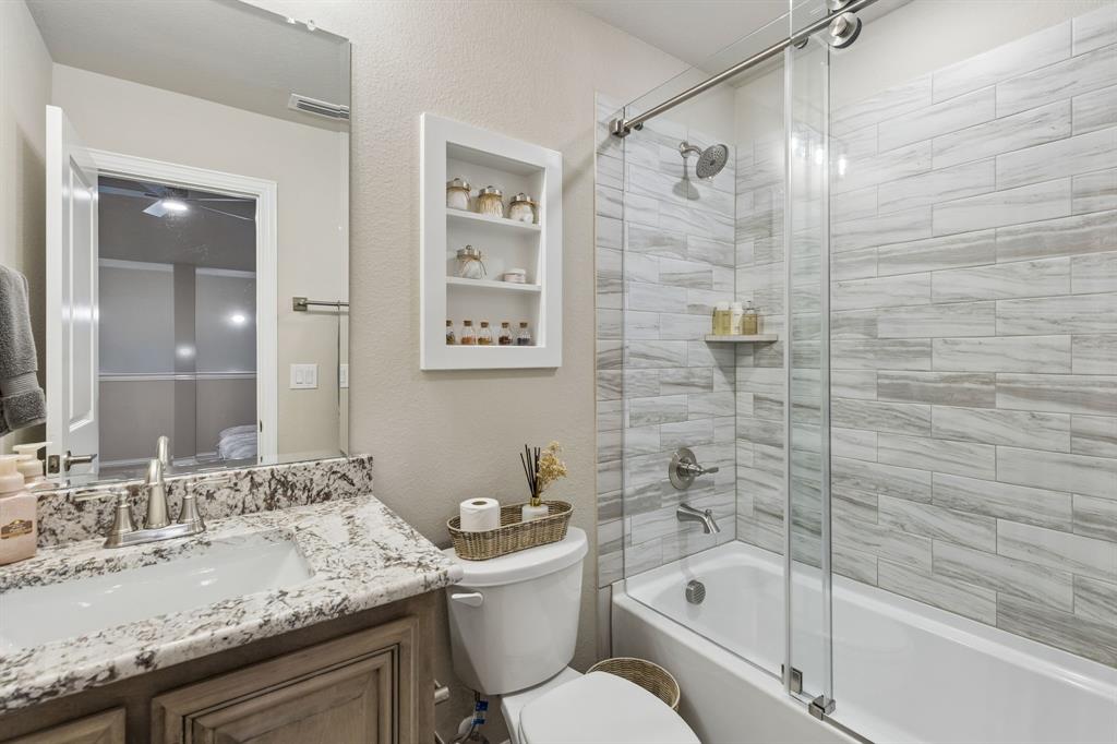 2137 Charming Frg Road Forney, TX 75126 - Photo 25 of 35 a bathroom with a granite countertop sink a toilet and shower