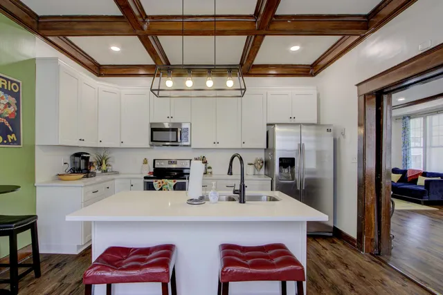 a kitchen with stainless steel appliances a refrigerator a sink a stove and white cabinets