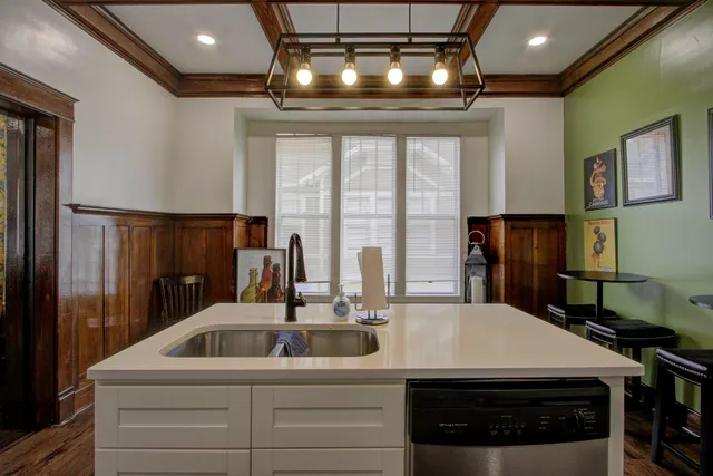 a kitchen with a sink stainless steel appliances and chandelier