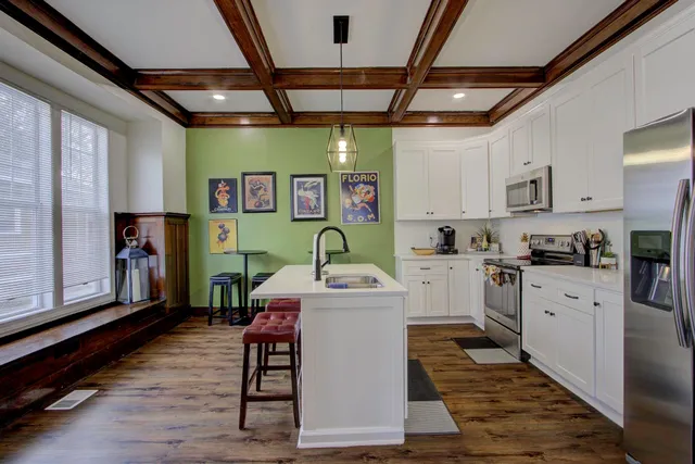 a white kitchen with a sink window and stainless steel appliances