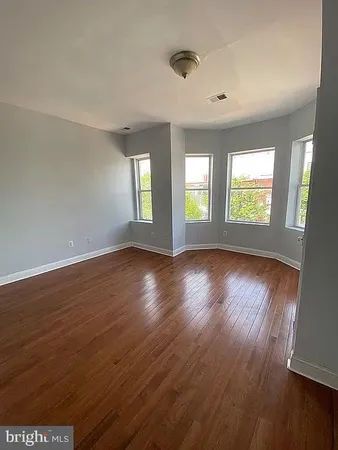 a view of an empty room with wooden floor and windows