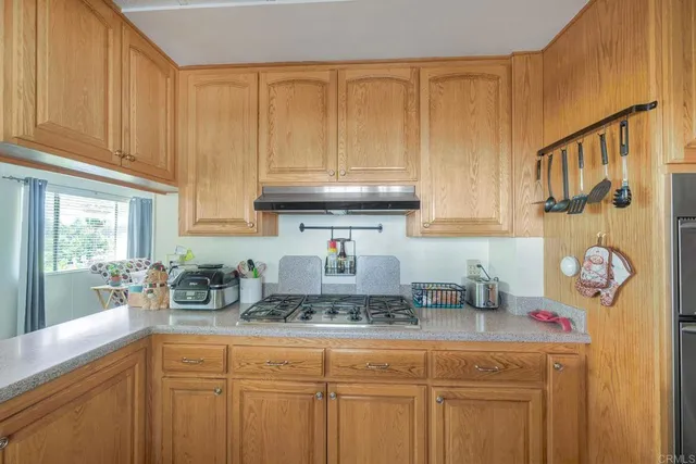 a kitchen with stainless steel appliances granite countertop a sink a stove white cabinets and a wooden floor