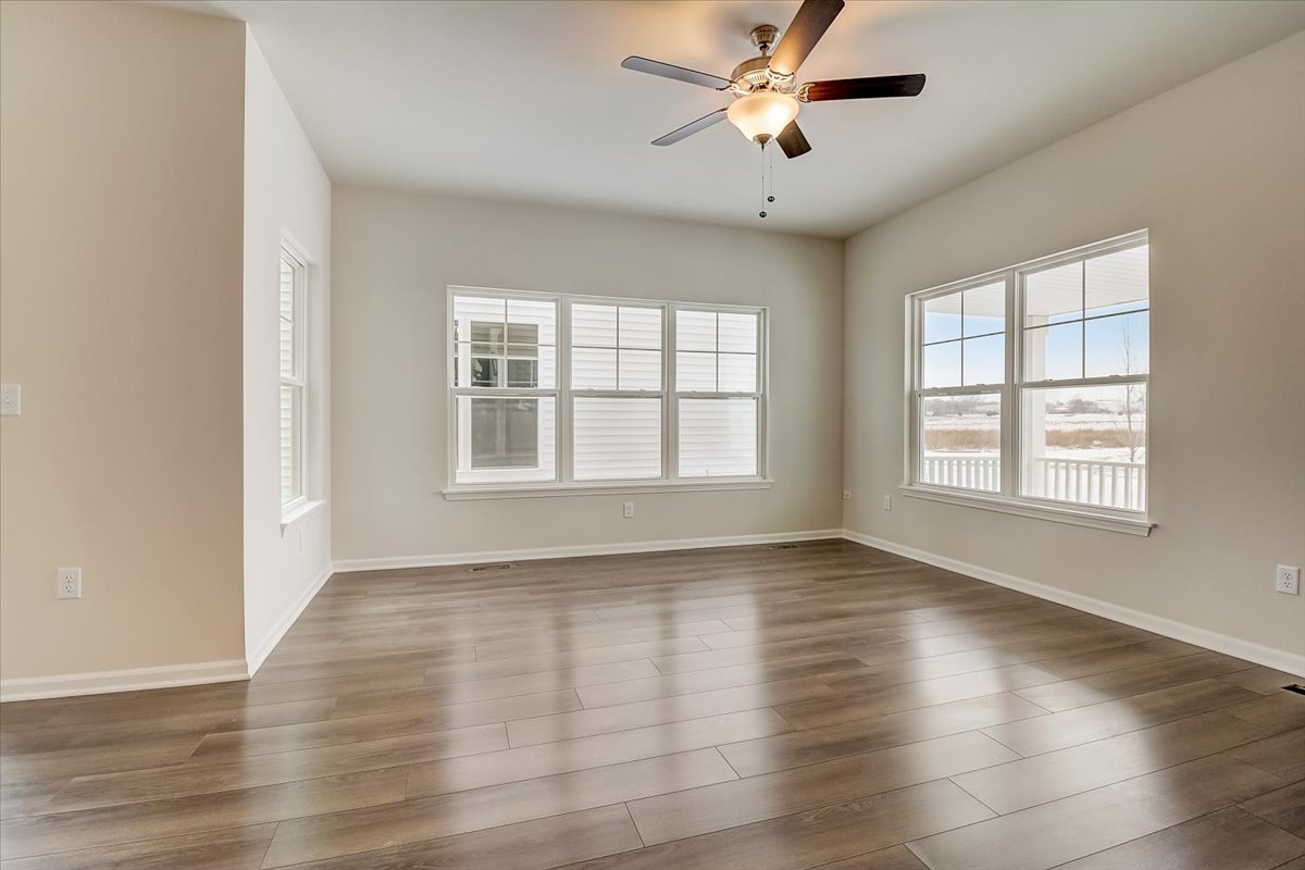715 Station Boulevard Elburn, IL 60119 - Photo 3 of 33 an empty room with wooden floor chandelier fan and windows