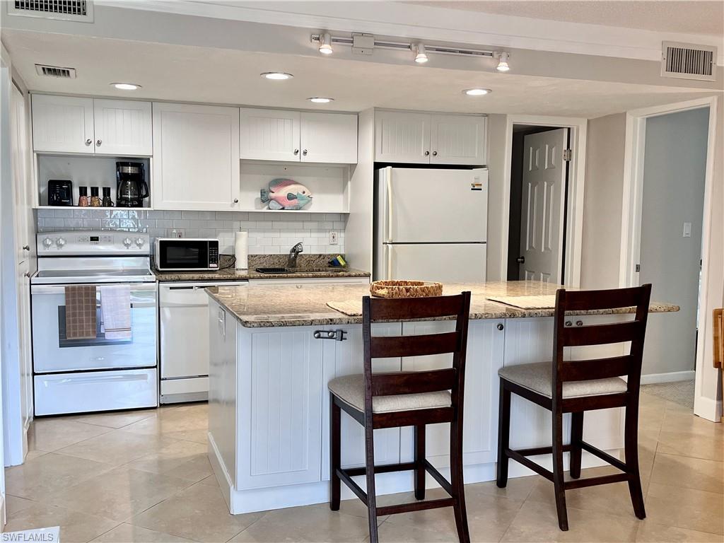 a kitchen with stainless steel appliances a stove a sink refrigerator and white cabinets with wooden floor