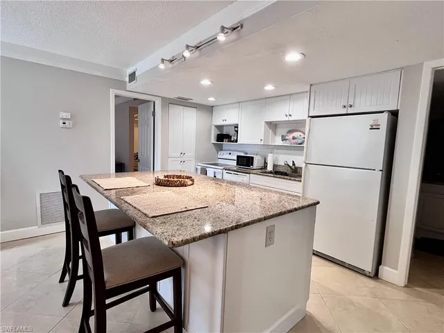 a kitchen with stainless steel appliances granite countertop table chairs refrigerator and microwave