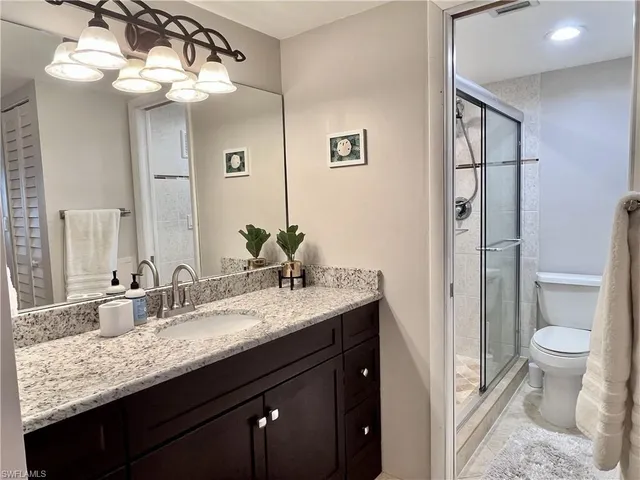 a bathroom with a granite countertop sink a toilet and a mirror