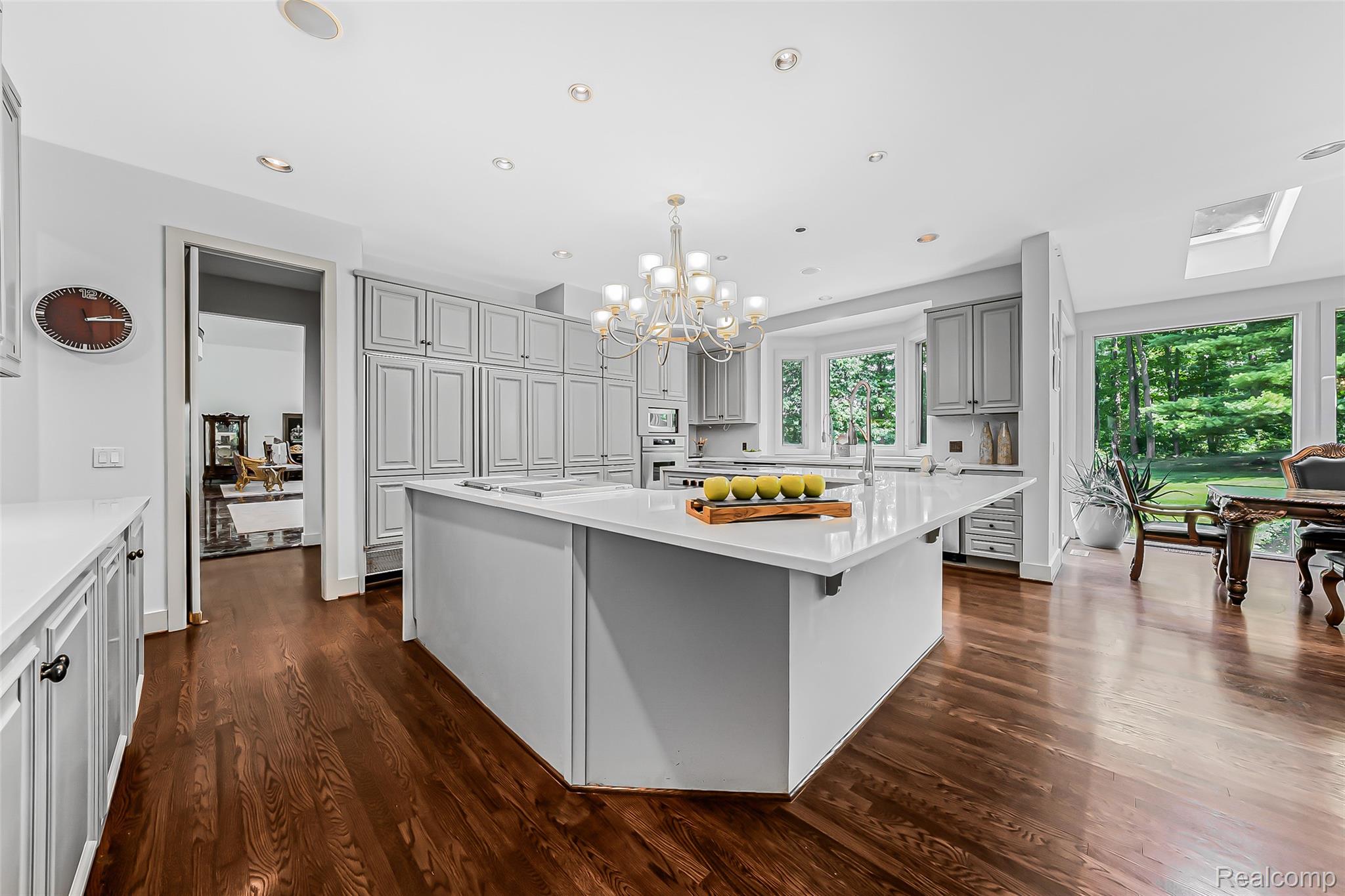 2785 Cranbrook Ridge Court Rochester, MI 48306 - Photo 43 of 99 Spacious kitchen featuring an expansive center island with countertop seating, floor-to-ceiling cabinetry, wood-finish flooring, and a large window overlooking the grounds