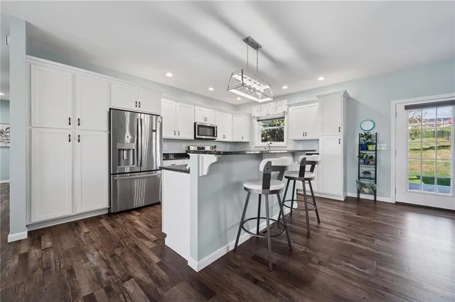 a kitchen with stainless steel appliances a dining table chairs refrigerator microwave and cabinets