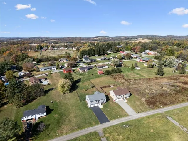 an aerial view of residential houses with outdoor space and trees