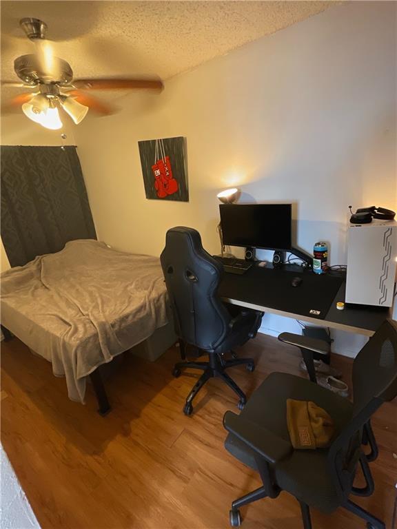 1011 West 23rd Street, Unit 101 Austin, TX 78705 - Photo 3 of 5 Bedroom with a textured ceiling, a ceiling fan, light wood-type flooring, and an office area