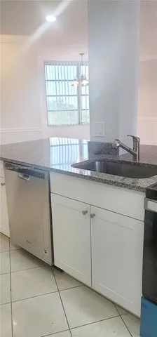 a kitchen with granite countertop white cabinets and a sink