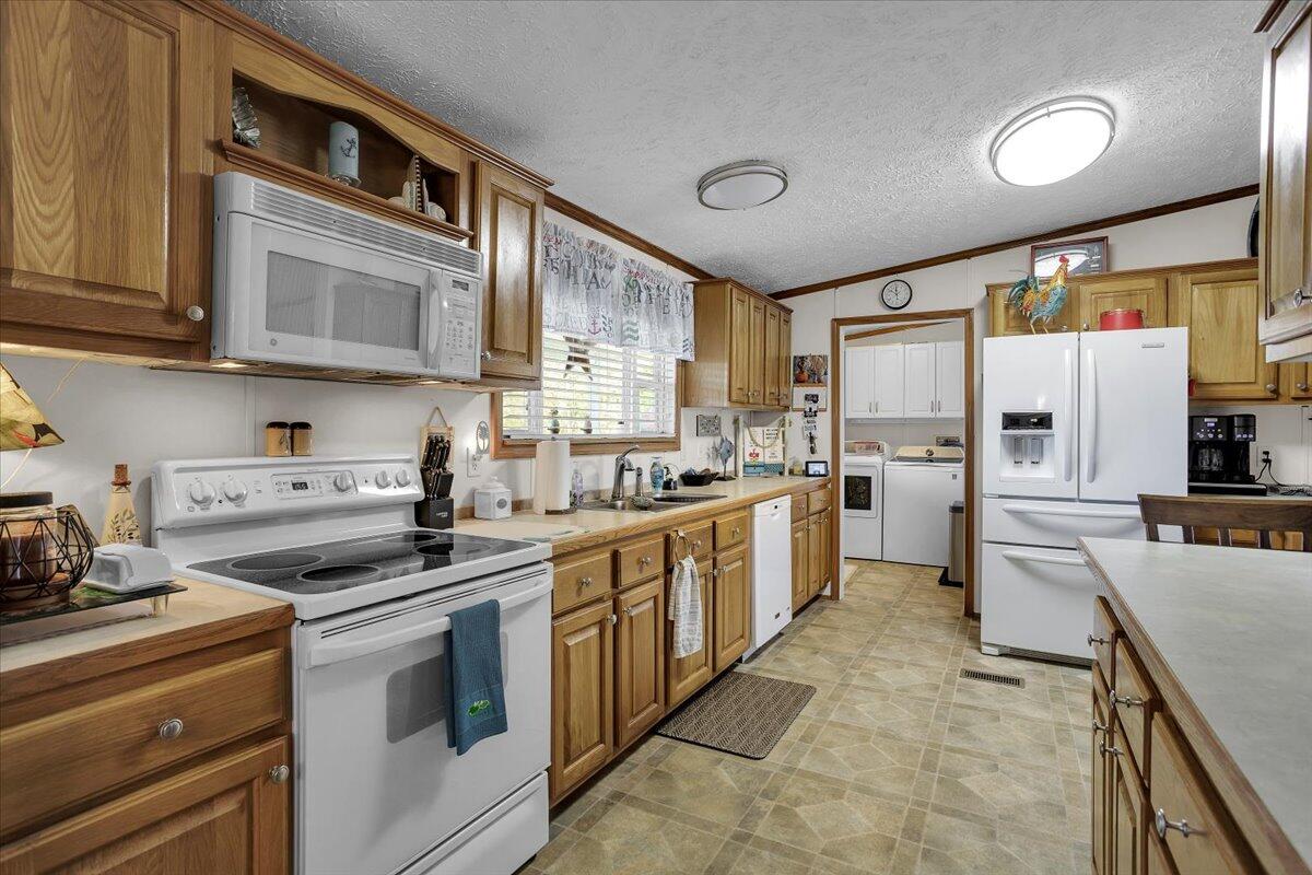 485 Big Cove Drive Penhook, VA 24137 - Photo 24 of 60 a kitchen with stainless steel appliances granite countertop a stove top oven a refrigerator a sink and dishwasher with white cabinets