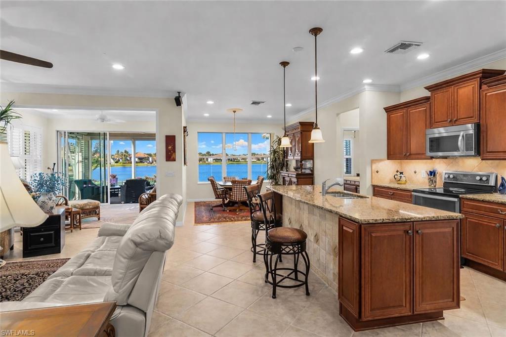 8595 Palermo Court Naples, FL 34114 - Photo 4 of 49 a open kitchen with stainless steel appliances kitchen island granite countertop a table chairs and a refrigerator