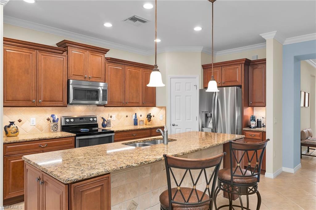 8595 Palermo Court Naples, FL 34114 - Photo 5 of 49 a kitchen with stainless steel appliances granite countertop a stove a sink a microwave a dining table and chairs