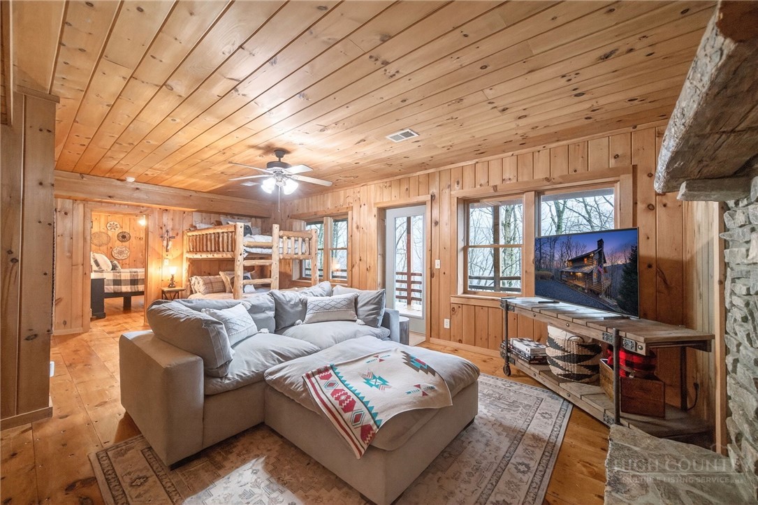 376 Yellow Bear Road Todd, NC 28684 - Photo 25 of 29 a living room with furniture a flat screen tv and a floor to ceiling window