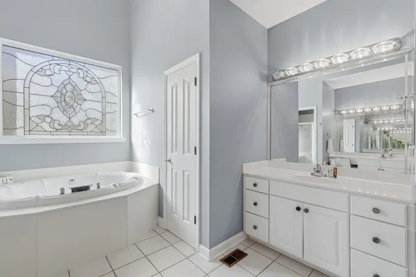 a spacious bathroom with a double vanity sink mirror and bathtub