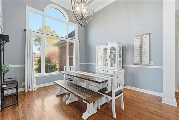 a dining room with wooden floor and a chandelier