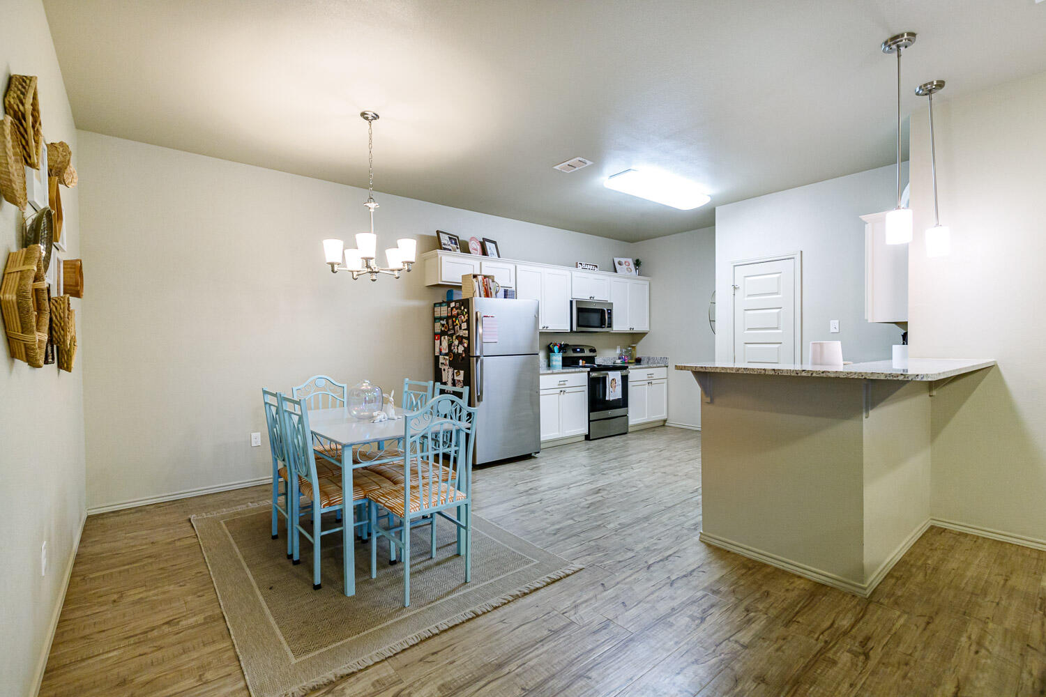6702 Pontiac Avenue Lubbock, TX 79424 - Photo 13 of 41 a kitchen with stainless steel appliances kitchen island granite countertop a refrigerator a stove a dining table and chairs with wooden floor