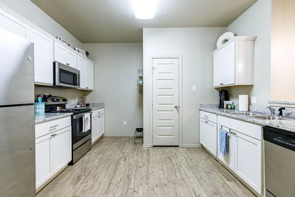 a kitchen with granite countertop a refrigerator stove top oven and sink