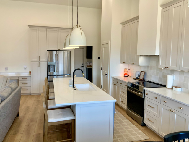 277 West 800 South Monroe, UT 84754 - Photo 5 of 46 Kitchen with stainless steel appliances, an island with sink, white cabinets, and a high ceiling