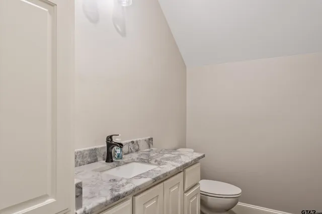 a bathroom with a granite countertop toilet and sink