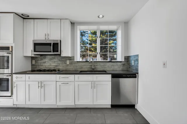 a kitchen with granite countertop white cabinets and stainless steel appliances