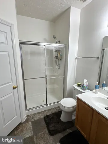 a bathroom with a granite countertop toilet a sink and a mirror