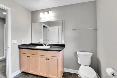 a bathroom with a granite countertop toilet sink and mirror