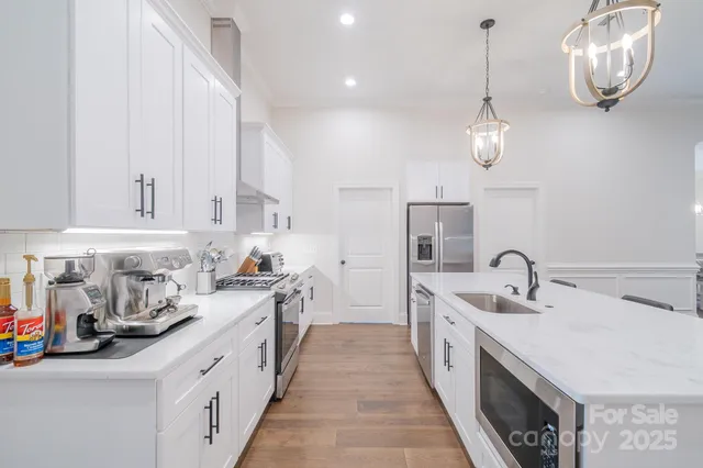 a kitchen with kitchen island granite countertop a sink stainless steel appliances cabinets and a counter top space