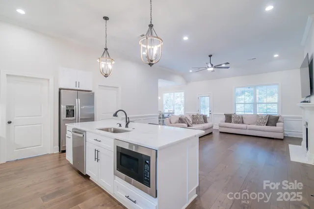 a open kitchen with stainless steel appliances granite countertop a sink a stove and a wooden floors
