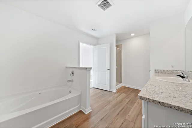 a bathroom with a granite countertop sink and a bathtub
