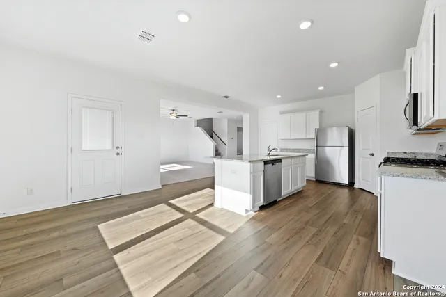 a large white kitchen with wooden floors and stainless steel appliances