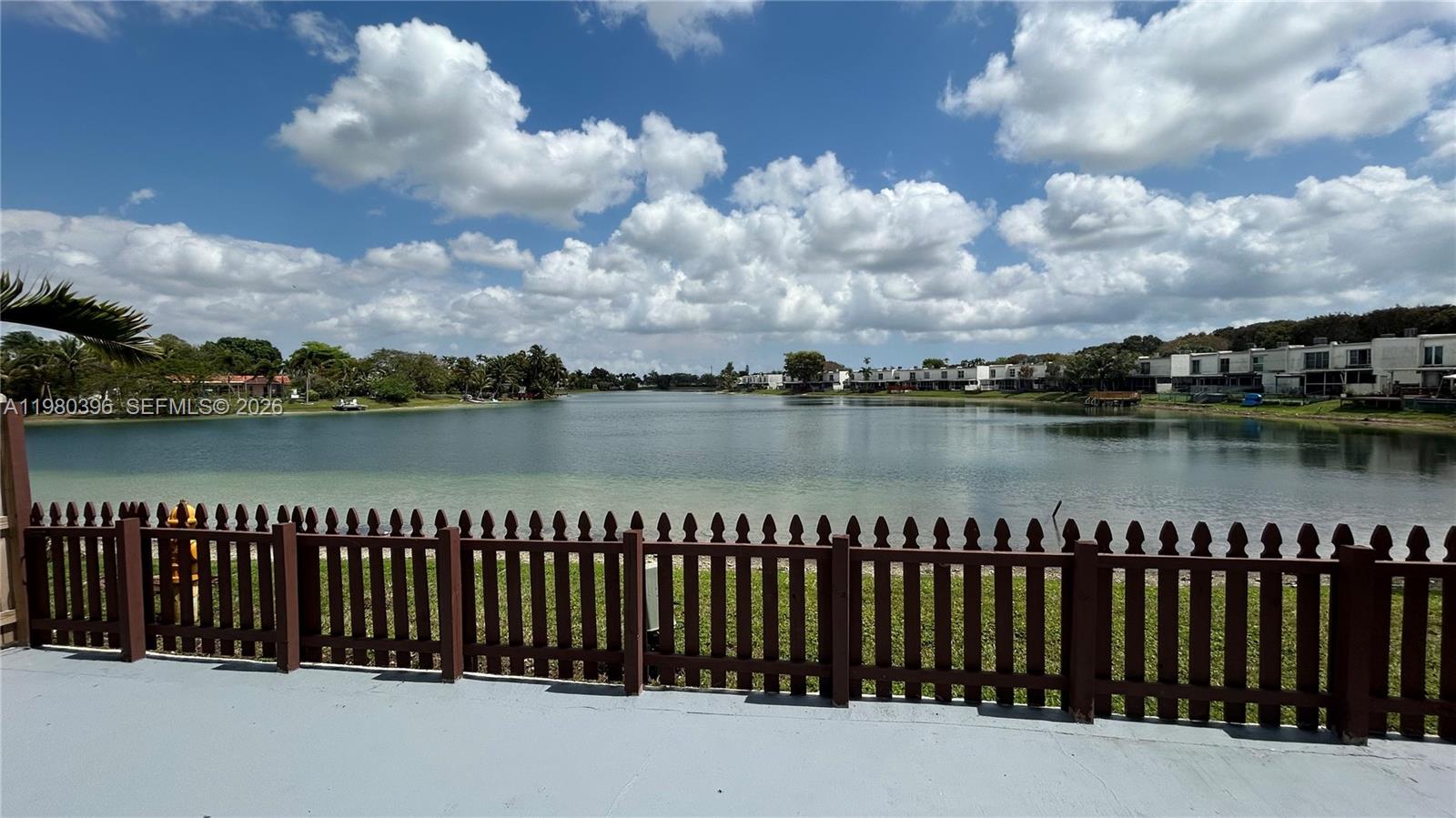 8307 Southwest 142nd Avenue, Unit E112 Miami, FL 33183 - Photo 12 of 12 a balcony with lake view and wooden fence