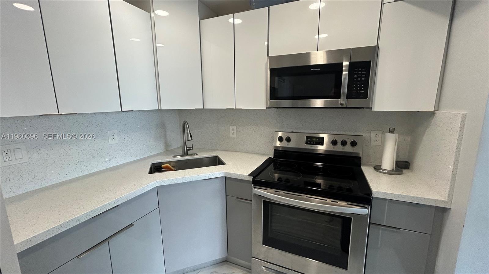 8307 Southwest 142nd Avenue, Unit E112 Miami, FL 33183 - Photo 4 of 12 a kitchen with stainless steel appliances a stove a microwave and cabinets