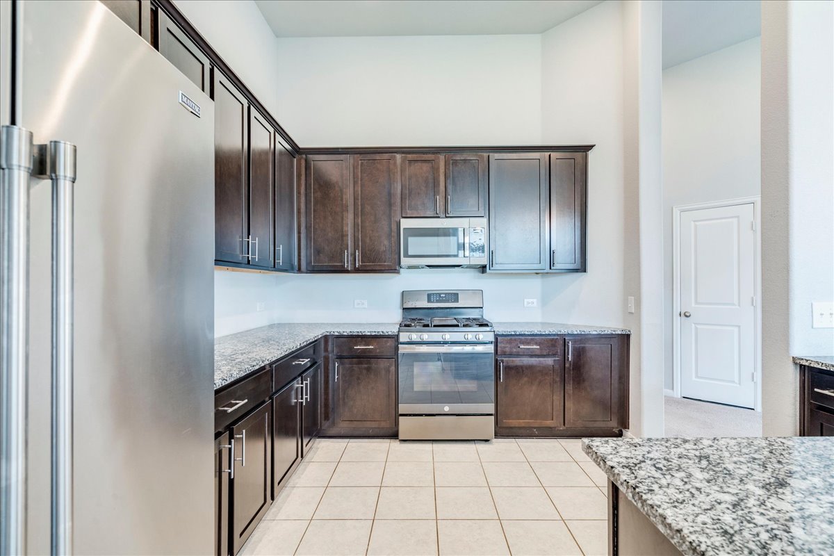 275 Cherrystone Loop Buda, TX 78610 - Photo 11 of 33 Large kitchen featuring granite countertops, espresso cabinets, stainless appliances and tons of counter and cabinet space.