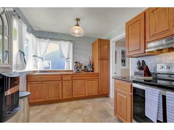 a kitchen with granite countertop a sink cabinets stainless steel appliances and a window