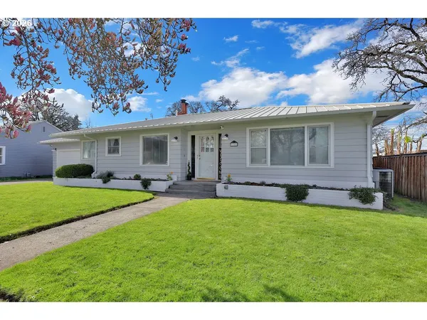 a view of a house with a backyard and a tree